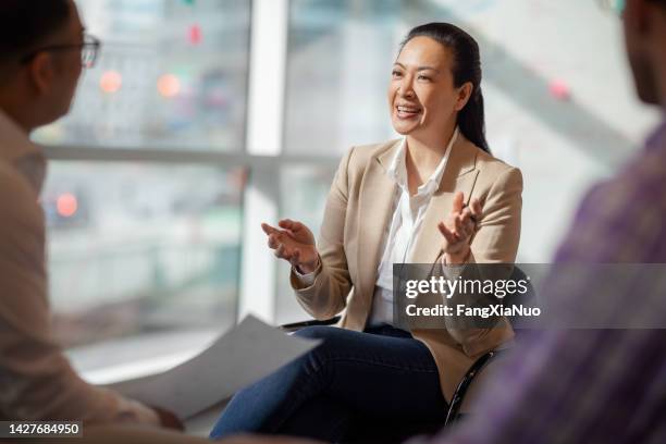 donna matura multirazziale asiatica ispanica delle isole del pacifico che parla con i colleghi nell'ufficio commerciale in riunione - mature women office foto e immagini stock