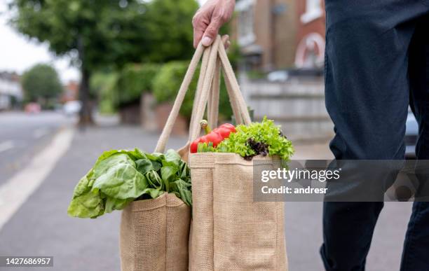 close-up on a man carrying a shopping bag with groceries on his way home - reusable bag stock pictures, royalty-free photos & images