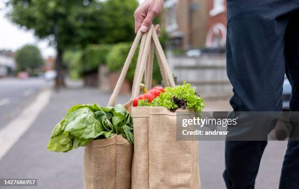 close-up on a man carrying a shopping bag with groceries on his way home - återanvändbar kasse bildbanksfoton och bilder