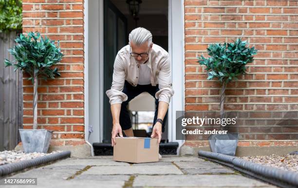 man receiving a package on his doorway - picking up mail stock pictures, royalty-free photos & images