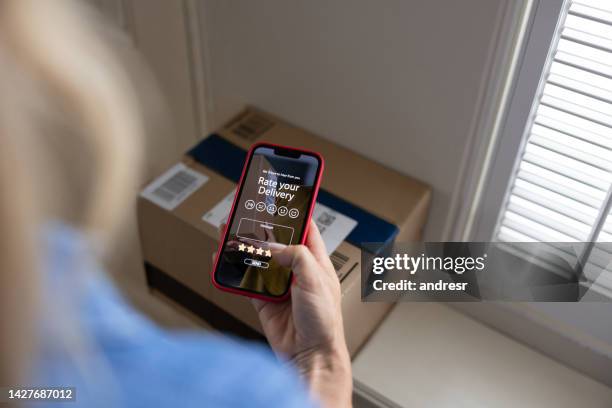woman rating her delivery experience after getting a package at home - satisfaction rating stock pictures, royalty-free photos & images