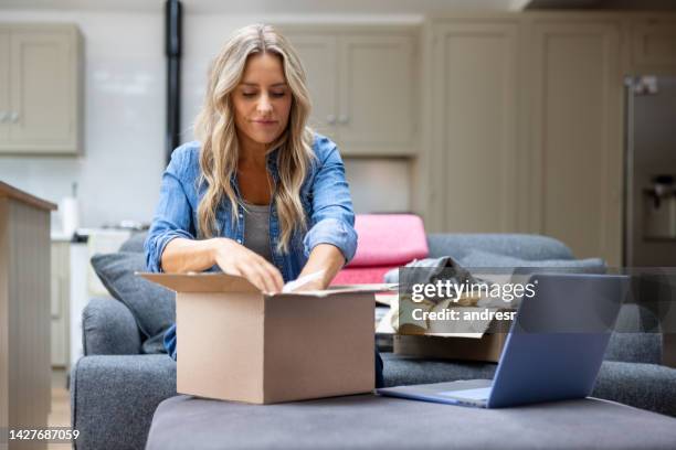 woman opening a package after shopping online - online shopping opening package stockfoto's en -beelden