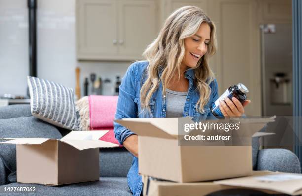 woman opening a package at home after shopping online - online shopping opening package stockfoto's en -beelden