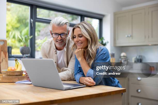 pareja feliz que paga facturas en línea usando una computadora portátil - happy couple at home fotografías e imágenes de stock