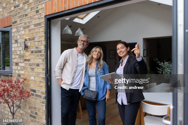 real estate agent showing a house for sale to a couple - couple pointing imagens e fotografias de stock