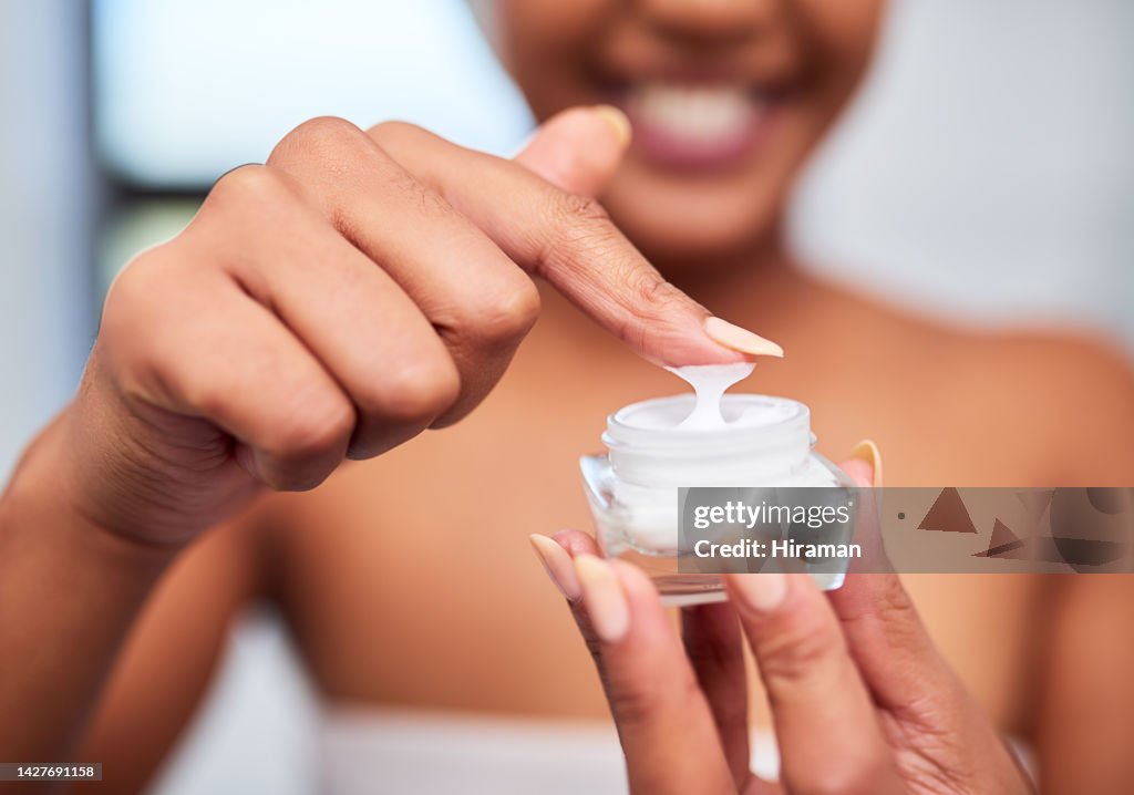 Skincare product, dermatology and black woman with beauty cream for a healthy, clean and glowing face. Wellness, hands and young African girl applying body lotion on finger in the bathroom close up