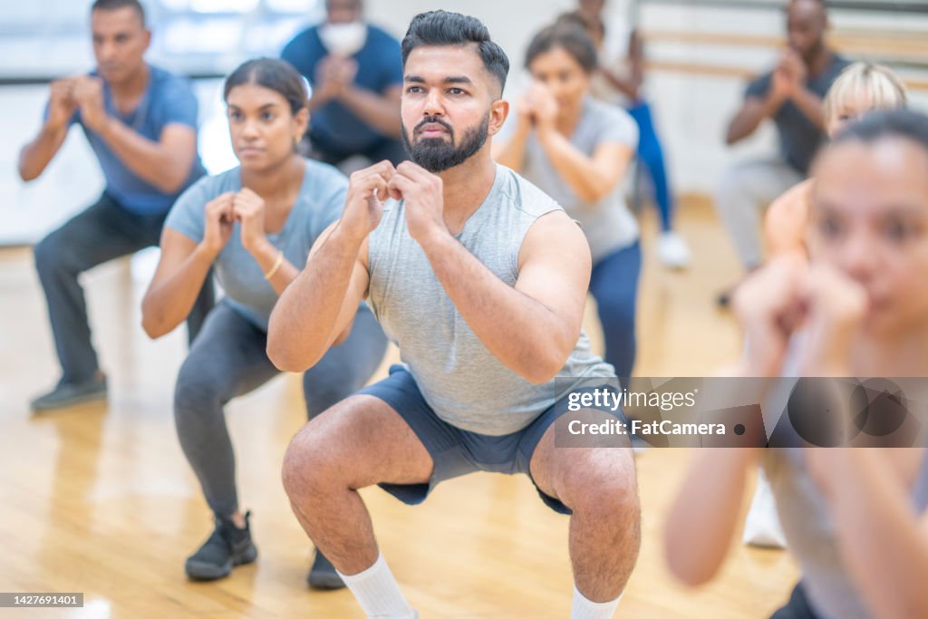 Adults Holding Squats in a Fitness Class