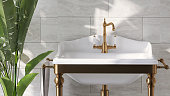 Luxury and classic design of bathroom vanity with brass legs, white rectangle ceramic washbasin and banana plant with sunlight from window on marble wall