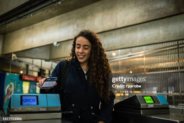 a woman entering the subway station with a qr code ticket on her cellphone - entering turnstile stock pictures, royalty-free photos & images