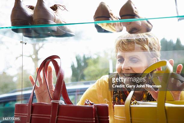 woman looking at handbags in boutique window - luxus shopping stock-fotos und bilder