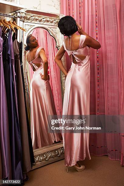 woman trying on dresses in boutique shop - woman mirror dress stock-fotos und bilder