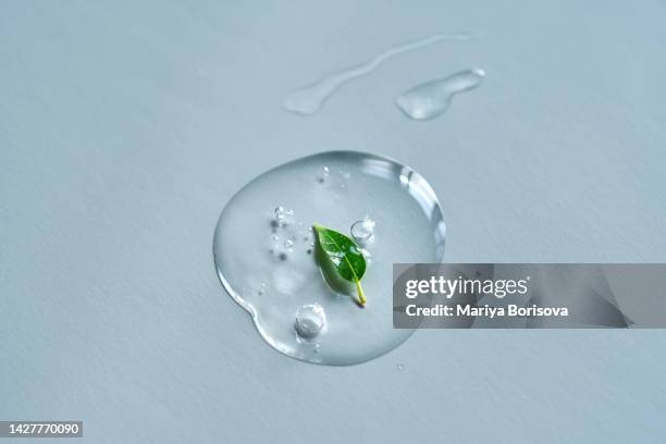 a drop of cosmetic liquid gel or micellar water with a leaf on a blue background. - oil water treatment stock pictures, royalty-free photos & images