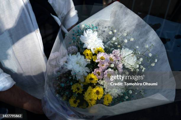 Woman holds a flower bouquet as she waits in line at a park near the Nippon Budokan, the venue of the state funeral for former Japanese Prime...