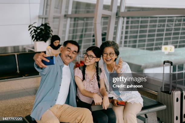 grandparents with granddaughters taking a selfie in the airport - airport sitting family stock pictures, royalty-free photos & images