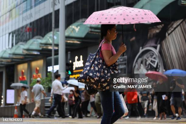Woman uses an umbrella to shelter from the rain in Central, a financial hub in Hong Kong on July 3, 2023.