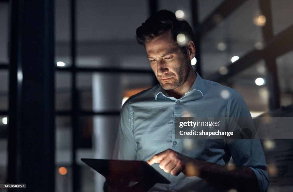 Business man, tablet and working late at night while browsing the internet, doing online research or checking trading stats. Serious entrepreneur using information technology for digital marketing