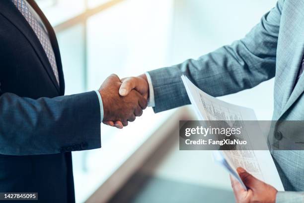 hands of asian african-american mature businessmen shaking hands in bright business office during meeting wearing suits - fiduciary responsibility stock pictures, royalty-free photos & images