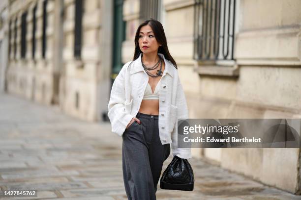 May Berthelot wears a black large chains large necklace from Chanel, a white embroidered oversized cardigan from Barrie, high waist dark gray wide...