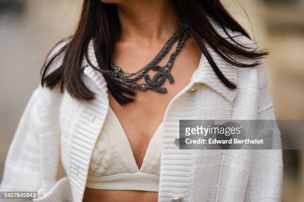 May Berthelot wears a black large chains large necklace from Chanel, a white embroidered oversized cardigan from Barrie, a white latte V-neck /...