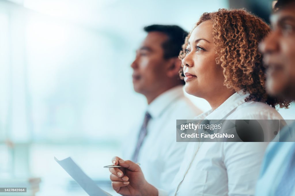 Japanese African-American mature businesswoman student sitting learning listening in education training seminar meeting in business office classroom with multiracial colleagues