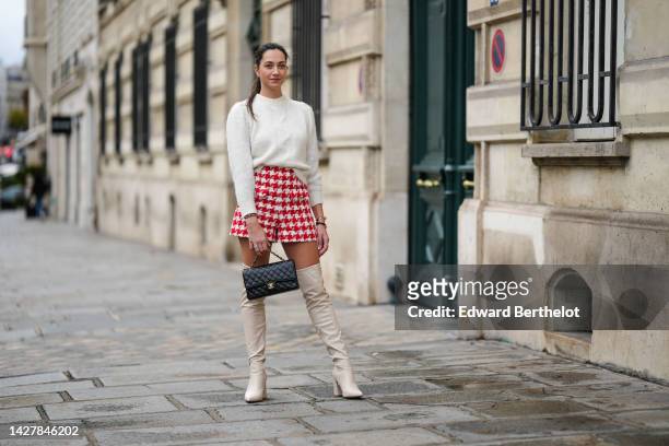 Alice Mouzon wears a white braided wool / puffy shoulder pullover from Kookai, white latte and red houndstooth print pattern shorts from Sandro, gold...