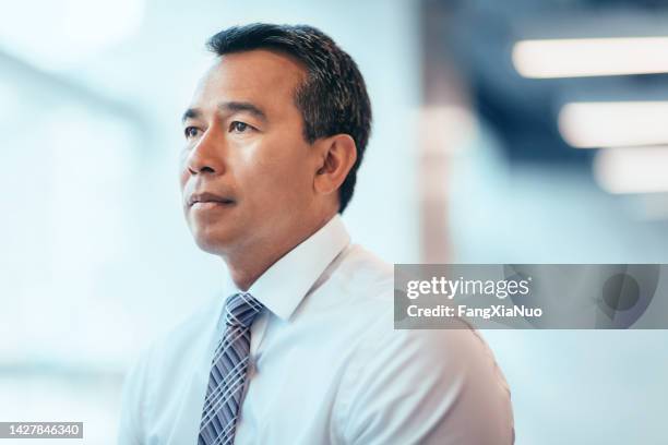 portrait of asian mature businessman serious looking away concerned thinking about future in bright business office in businesswear - emotional intelligence stock pictures, royalty-free photos & images