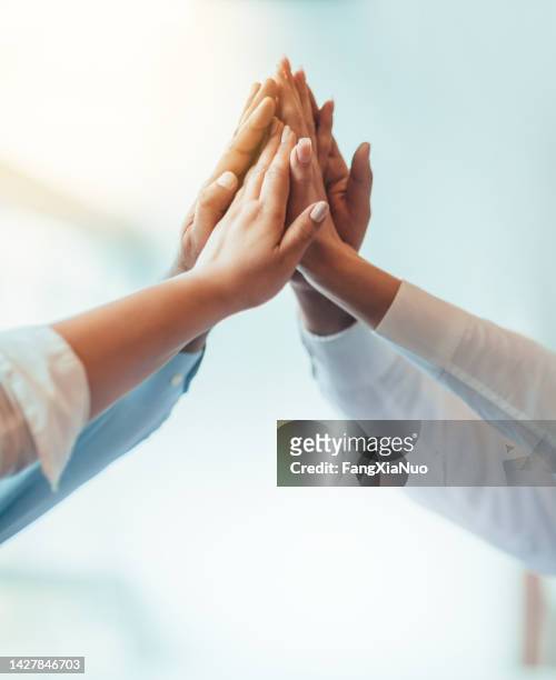 multiracial group of students stacked hands high-five in agreement achievement success aspiration smiling in bright business office classroom - teamwork human hand team stock pictures, royalty-free photos & images