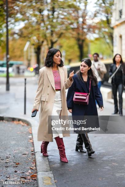 Guest wears a red and white striped print pattern t-shirt, a beige long coat, a white wrap knees skirt, red shiny leather pointed heels knees boots,...