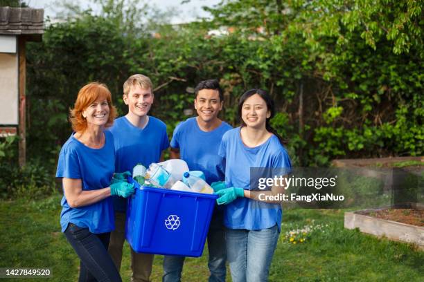 portrait of multiracial group of young people stand with mature woman project manager leader volunteer holding recycle bin with plastic bottles within community garden park during cleanup of environment - mixed recycling bin stock pictures, royalty-free photos & images