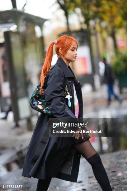 Guest wears gold earrings, a black long coat, black tights, black high socks, a black with green / blue / beige orange flower print pattern shoulder...