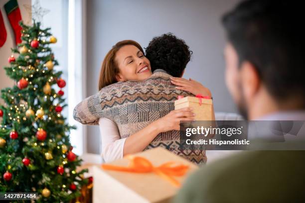 mother hugging her son and thanking him for her christmas present - hug christmas stock pictures, royalty-free photos & images