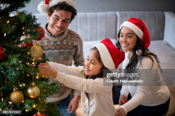 famiglia felice che decora l'albero di natale - decorare l'albero di natale foto e immagini stock
