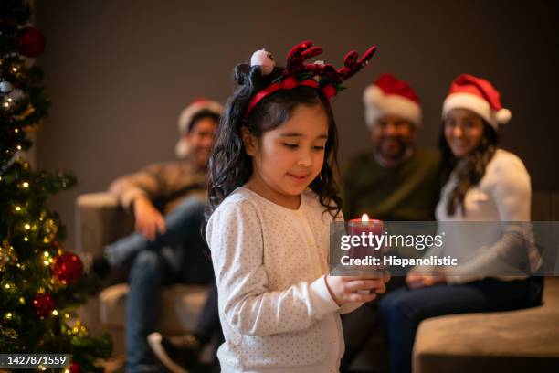 girl celebrating christmas with her family and holding a candle - christmas candles stockfoto's en -beelden