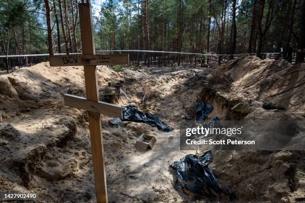 An open pit and a cross mark where 17 Ukrainian soldiers were buried, after Ukrainian forensic and war crimes investigators completed their...