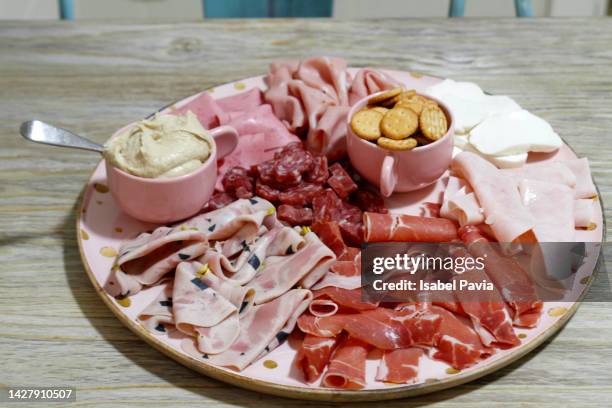 charcuterie board with ham, salami, prosciutto, hummus, cheese and pretzels - charcutería fotografías e imágenes de stock