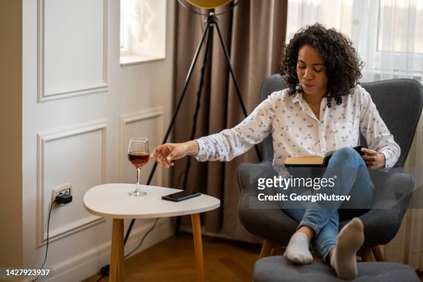 full body shot of woman in lounge room - brown hair drink wine stock pictures, royalty-free photos & images