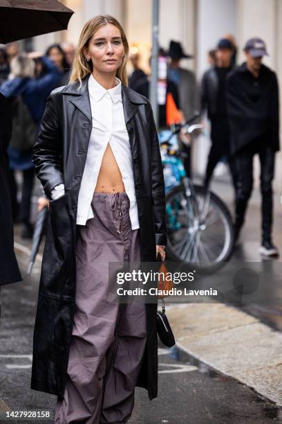 Chiara Capitani is seen wearing a black leather trench coat, beige Salomon sneakers and white shirt outside the Salvatore Ferragamo show during the...