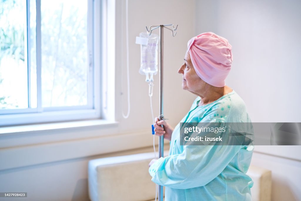 Patient wearing headscarf standing by IV drip