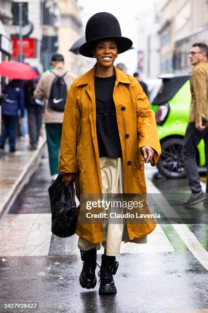 June Ambrose is seen wearing a mustard long trench coat, black felt wool oversized high hat, beige pants, black Prada ankle boots and black MM6...