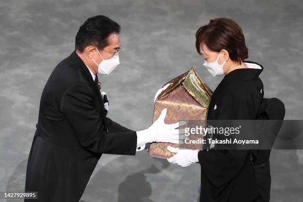 Japan's Prime Minister Fumio Kishida hands off the urn containing Shinzo Abe's ashes to the widow of former Japanese prime minister Shinzo Abe, Akie...