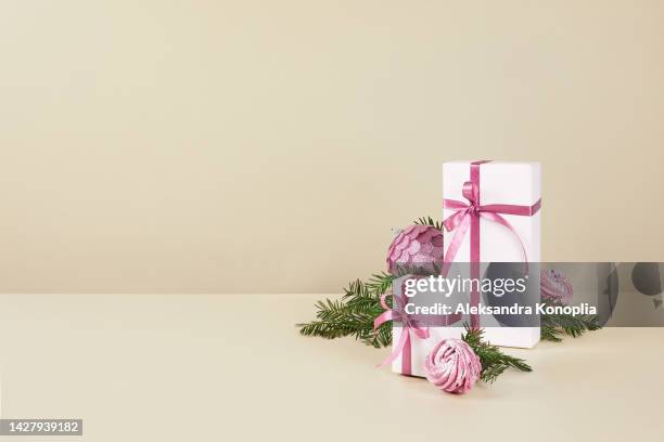 xmas still life composition with pastel pink christmas ornaments on solid beige background - tisch frontal stock-fotos und bilder