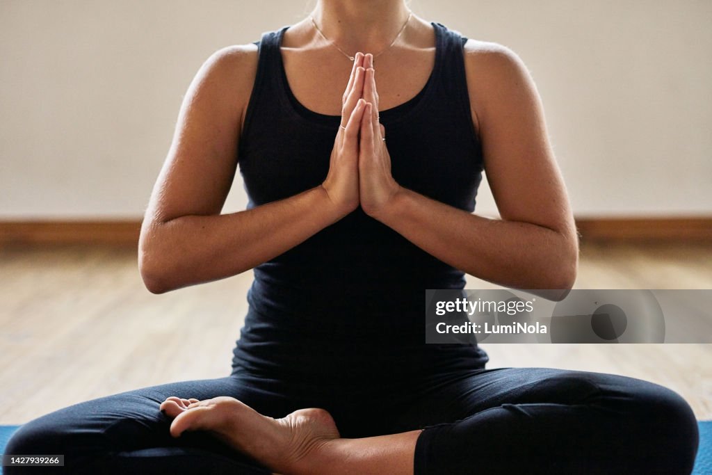 Yoga, pilates and zen woman in a lotus pose training body posture, mindfulness and peace in a calm studio or house. Wellness, fitness and relaxed person in meditation sitting in a easy position