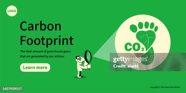 a man looks at the carbon footprint symbol through a magnifying glass, the concept of sustainability, and environmental protection - carbon footprint reduction stock illustrations