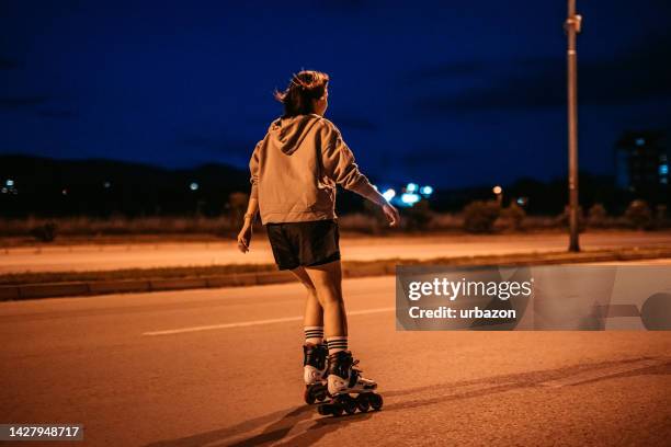 young woman roller skating down the street at night - skate night stock pictures, royalty-free photos & images