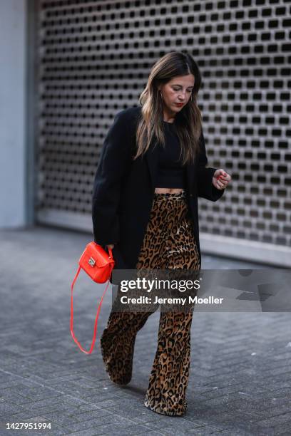 Silvia Cristina Alves Machado is seen wearing black oversize blazer from Acne Studios, brown leopard pattern Dries van Noten wide leg pants, orange...