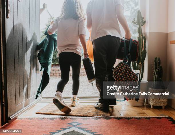 two young children wearing school uniforms exit their front door - busy parent stock pictures, royalty-free photos & images