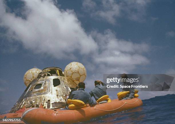 The crew of Apollo 11 in a raft beside the command module Columbia as they await pickup by the USS Hornet after splashdown at the end of the NASA...