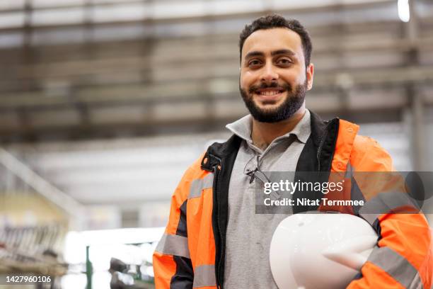 organization, people and technology, towards continuing improvement in manufacturing industry. portrait of product development engineers holding a hardhat while standing in the production line of engineering parts. - iranian people stock pictures, royalty-free photos & images