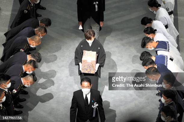 Akie Abe, widow of former Prime Minister of Japan Shinzo Abe, carries a box containing her husband's ashes, behind Japanese Prime Minister Fumio...