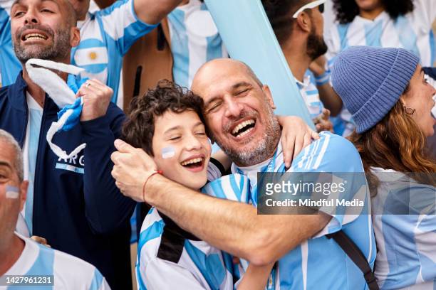 argentinian father and son embracing each other while celebrating score at football match - argentinsk kultur bildbanksfoton och bilder